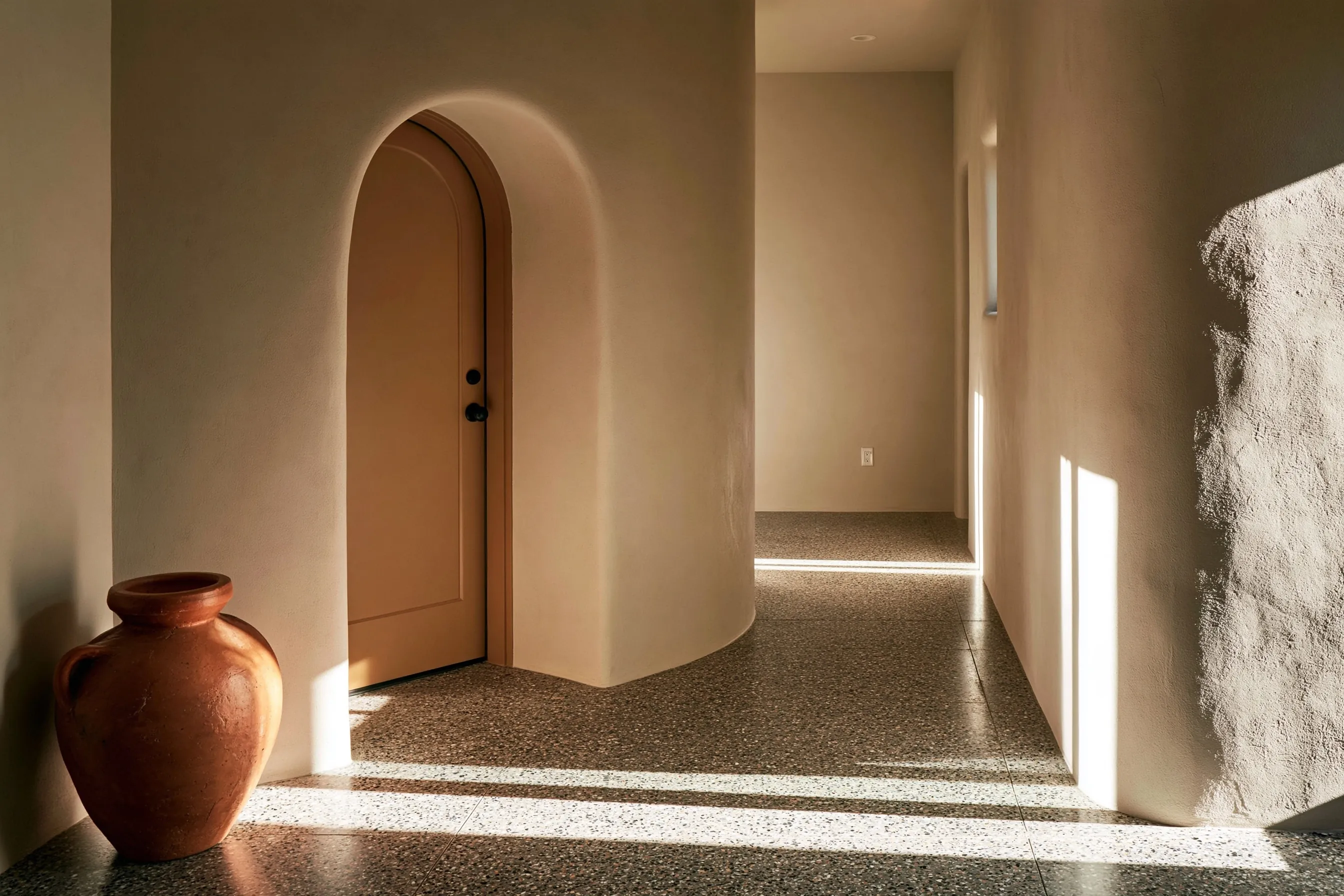 Entry hall and corridor with a salt-and-pepper fine-aggregate polished floor and an arched stucco doorway